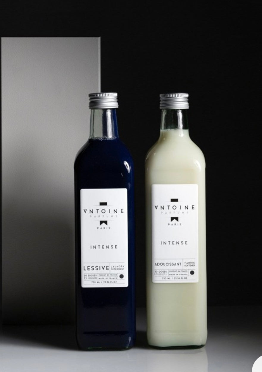 Two bottles of 'Antoine' products on a reflective surface with a dark background