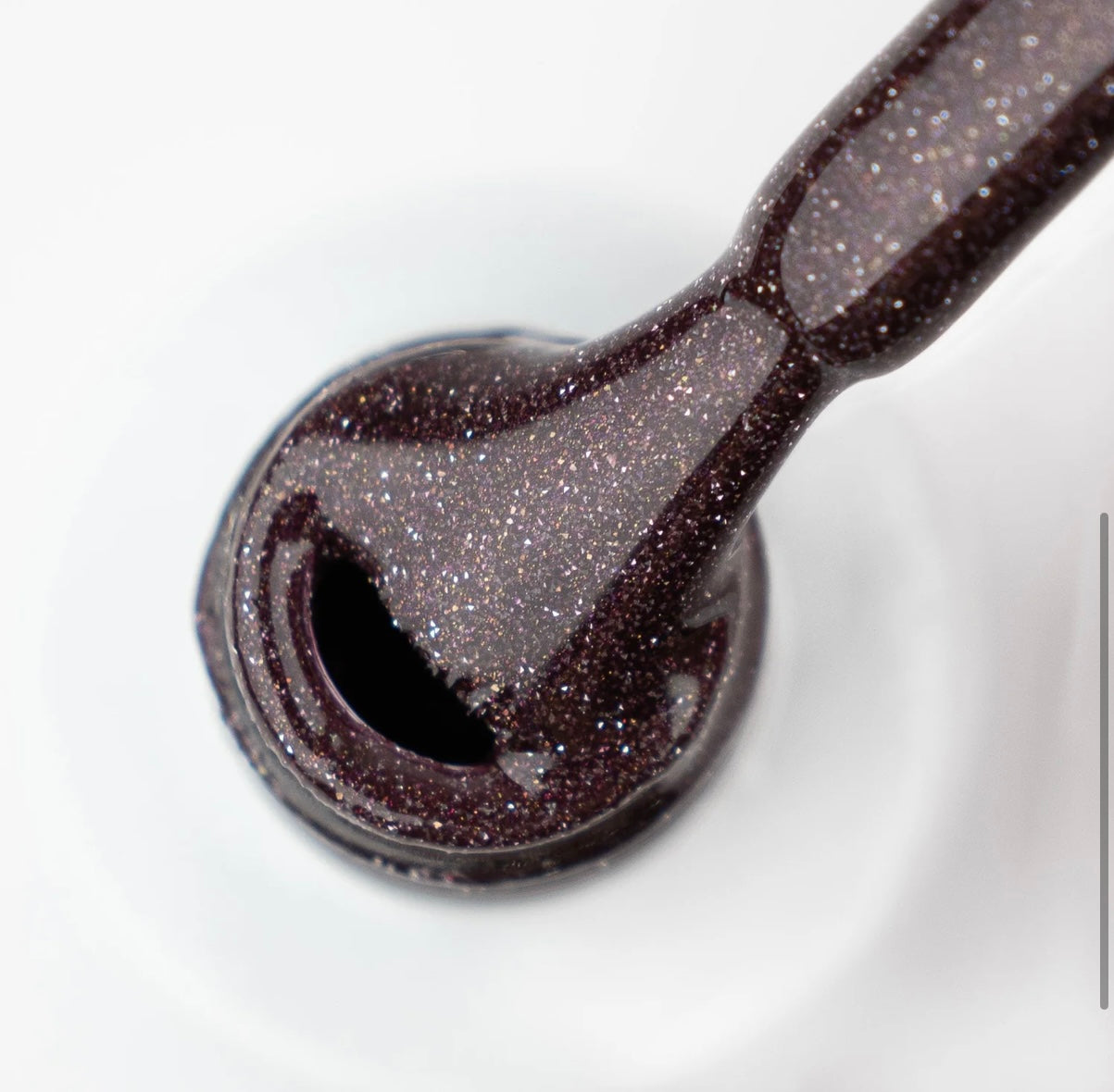 Close-up of a glittery black nail polish on a white background
