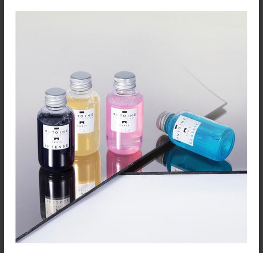 Four bottles of perfume with silver caps on a reflective surface